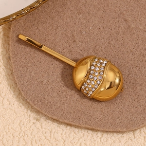 Macro shot of 18K gold plated acorn hair clip with white rhinestones on felt base