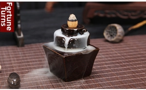 Detail of multi-tier ceramic backflow incense burner with flowing smoke effect on bamboo mat