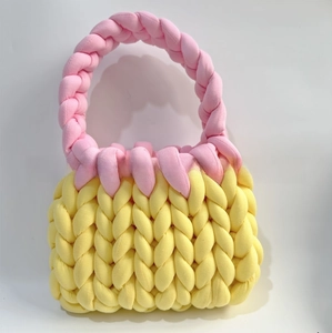 Close-up of handmade chunky knit handbag with yellow body and pink contrast handles