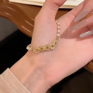 Elegant gold pearl bracelet featuring zircon-encrusted coin charms and a vintage design