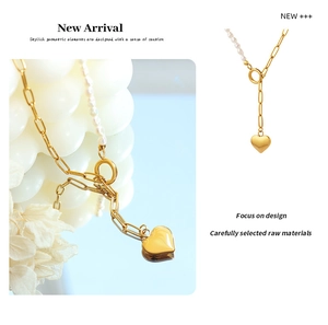 Detail of asymmetric gold paperclip chain and freshwater pearl necklace with heart pendant