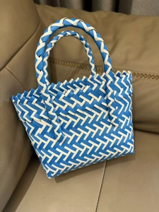 Detail of blue and white woven handbag showing reinforced handles and geometric texture