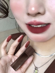 Close-up of deep red-brown matte liquid lipstick with velvet finish and sleek tube