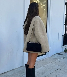 Vue arrière d'une veste beige en peau lainée avec bottes hautes et sac à chaîne