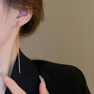 Boucles d'oreilles dorées à nœud et pampilles portées par un mannequin en tenue chic