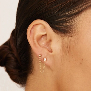 Close-up of 925 silver gold tassel earrings with zircon studs worn by a model