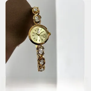 Détail d'une montre bijou dorée avec bracelet en zircon étincelant et cadran à quartz