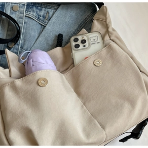 Detail view of beige nylon tote bag capacity showing a folding umbrella and smartphone