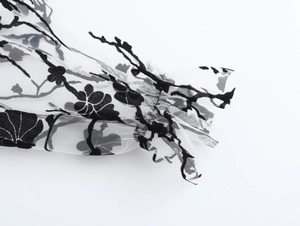 Detailed view of white sheer mesh sleeve with black floral print and ruffled cuffs