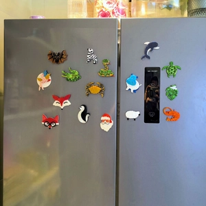 Collection of colorful handmade acrylic animal fridge magnets displayed on a refrigerator