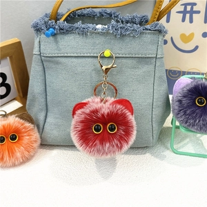 Dettaglio portachiavi mostro di peluche rosso con grandi occhi gialli su borsa