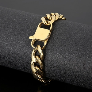 Macro detail of gold Cuban link bracelet with lobster clasp on black background