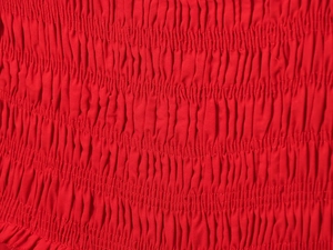 Close-up of red cotton midi dress showing detailed smocked texture and elastic pleats