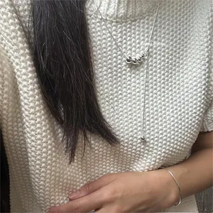 Detail of adjustable 925 sterling silver bead necklace and slim ring on white knit sweater