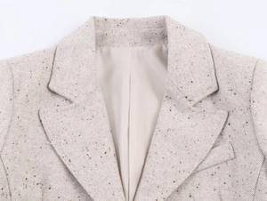 Gros plan du revers d'un blazer en tweed beige montrant la texture du tissu de luxe