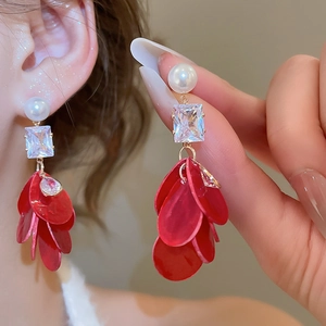 Macro shot of long earrings with red flower petals, square crystal and white pearl
