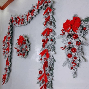 Close-up of snowy flocked Christmas wreath with red bows, berries and pine cones