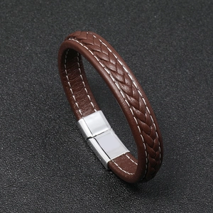 Detail of a brown braided leather bracelet with white stitching and silver magnetic clasp