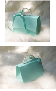 Detail of light blue gift box with pearl handle, ribbon bow and embossed floral pattern
