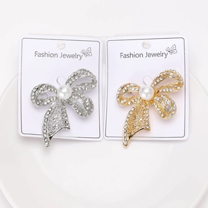 Detailed close-up of bow brooches with pearls and rhinestones on display cards