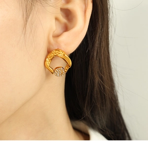 Detail view of gold geometric layered earrings with crystal drop on person's ear