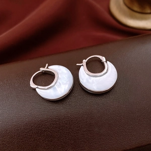 Detailed macro view of U-shaped silver earrings with white mother-of-pearl inlay