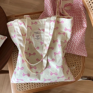 Détail de sacs fourre-tout en toile à motifs de nœuds roses avec bretelles renforcées