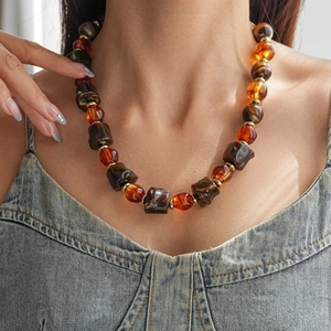 Gros plan sur les perles en acrylique ambré et les intercalaires dorés du collier