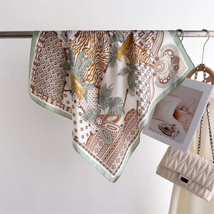 Detail of silk-like scarf featuring leopard print and palm leaves on a metal hanger