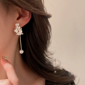 Eleganti orecchini a fiore con perle pendenti e strass indossati da una modella