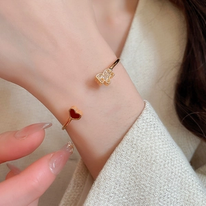 Detail of gold-tone open bangle featuring a zircon bear and red heart on wrist