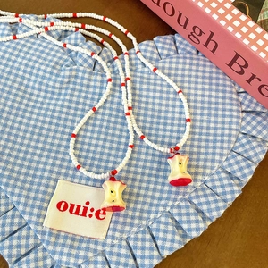 Beaded necklace set with red apple core charms on blue checkered heart fabric
