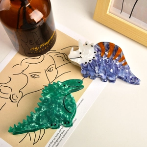 Detail of dinosaur hair claws made of acetate featuring green T-rex and blue triceratops