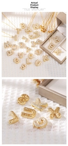 Macro detail of gold plated puffed initial pendant showing intricate cutout back patterns
