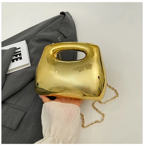 Close-up of golden mirror finish acrylic clutch with metallic handle and chain strap