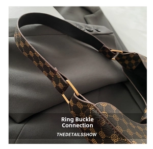 Close-up of golden metal buckle and vintage floral pattern on brown underarm bag