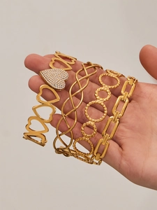 Macro view of four PVD gold plated hollow geometric bracelets with heart and link designs