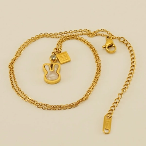Macro detail of golden bunny necklace with mother of pearl and engraved lucky charm