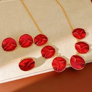 Detailed view of red enamel petal jewelry set with gold metal edges and elegant gold chain