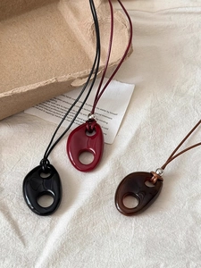 Detailed macro view of resin geometric oval pendants in black, red, and amber brown colors