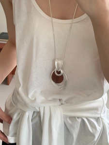 Detail of teardrop pendant necklace with hollowed matte silver frame and brown textured center