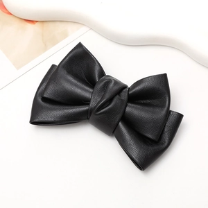 Macro detail of a black faux leather bow accessory with textured finish for phone cases