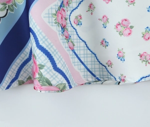 Détail de l'ourlet d'une robe en satin avec imprimé rose et motifs à carreaux bleus