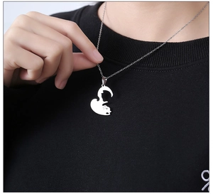 Close-up of polished stainless steel black and white cat hug pendant on a link chain