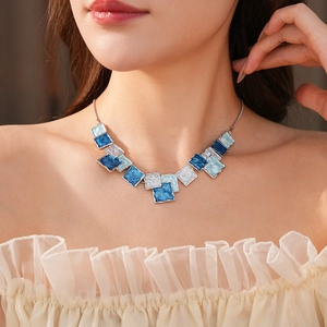 Close-up of blue geometric enamel square pendant necklace on model with silver chain