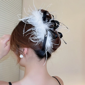 Detailed view of an elegant hair clip with white feathers and a black silk ribbon bow