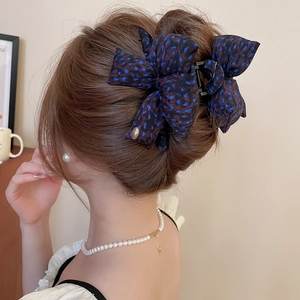 Detail of blue leopard print bow hair claw clip worn by model in a soft indoor setting