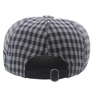 Detail of vintage plaid newsboy hat showing adjustable metal buckle and woven side label