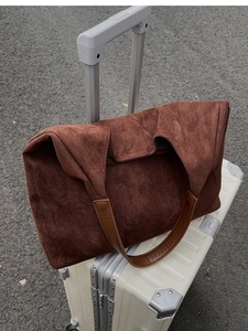 Detail of the brown suede tote bag featuring matte texture and smooth leather handles