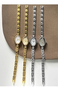 Détail de montres à quartz ovales avec chiffres romains et élégants bracelets en maille